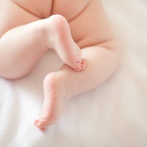 Baby laying prone on a white blanket, showing only their bottom