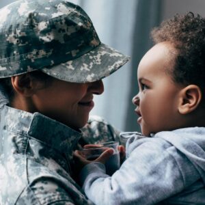 Parent and baby smile at each other in camo gear