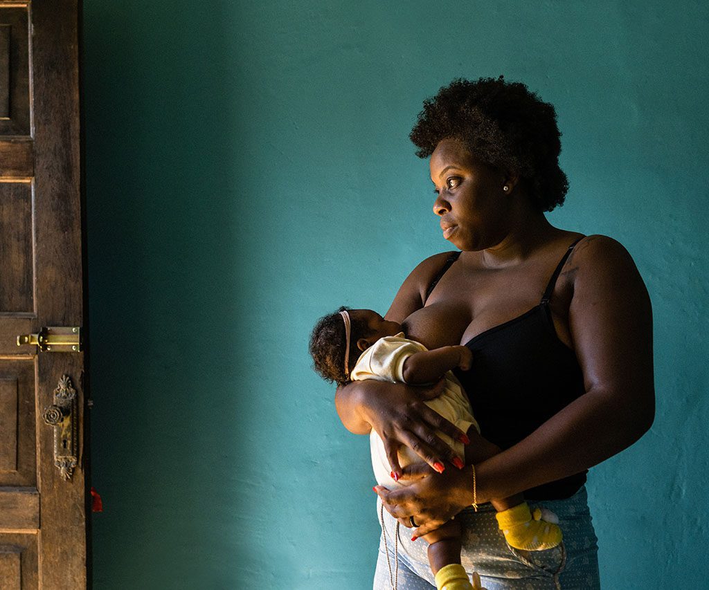 Standing woman breastfeeding at home