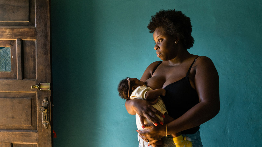 Standing woman breastfeeding at home