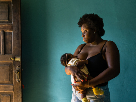 Standing woman breastfeeding at home